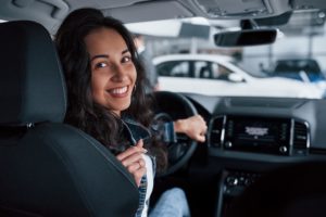 Moving backwards. ute girl with black hair trying her brand new expensive car in the automobile salon.